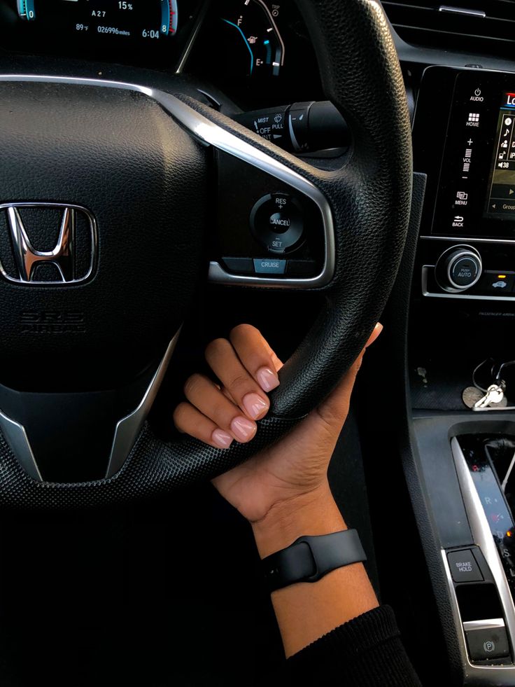 a person driving a car with their hands on the steering wheel and dashboard controls in front of them