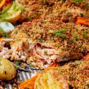 some food that is laying on top of a pan with potatoes and carrots next to it