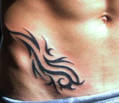 a man's stomach with a tattoo design on the side and his lower back