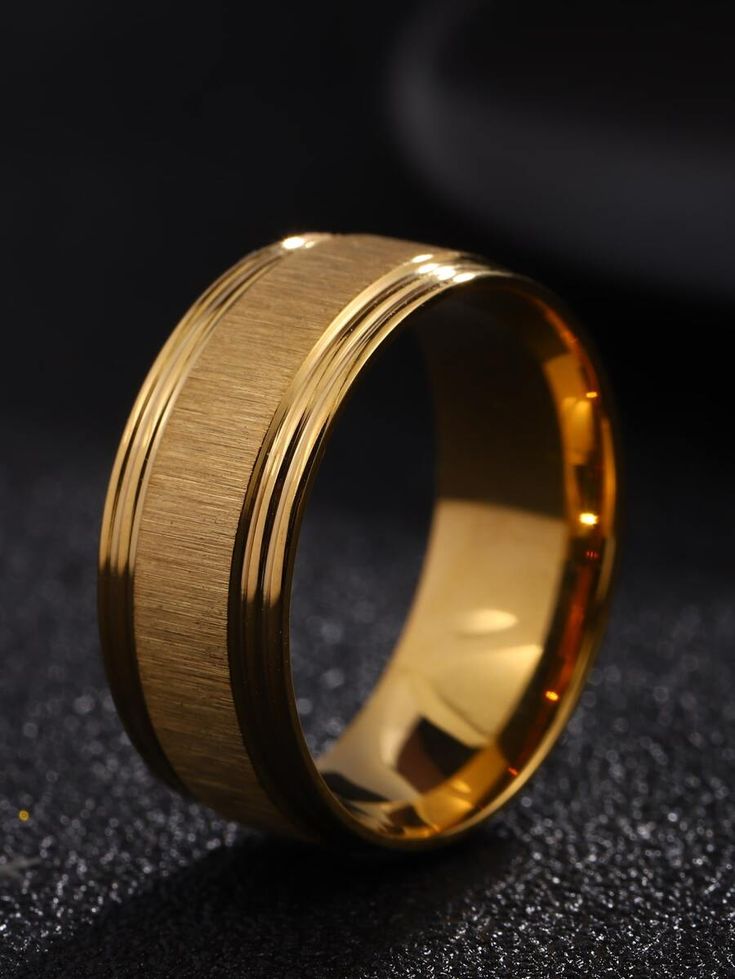 a gold wedding ring on a black surface