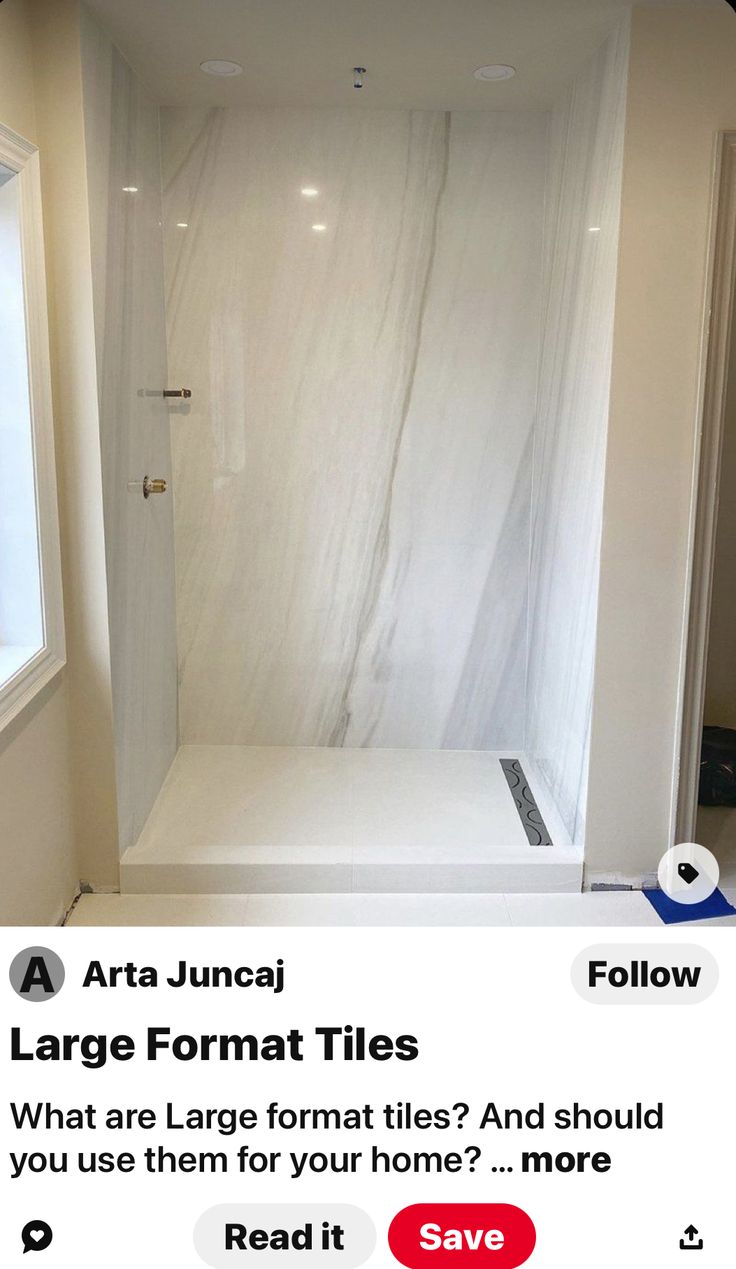 an empty bathroom with white marble walls and flooring in the shower area, next to a window