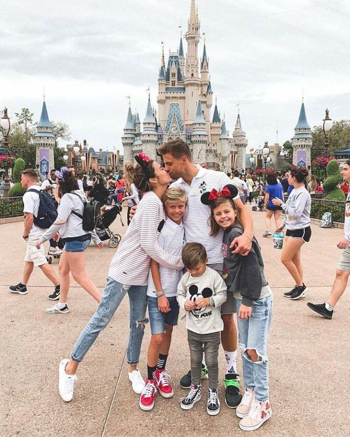 a group of people standing around each other in front of a castle at disney world