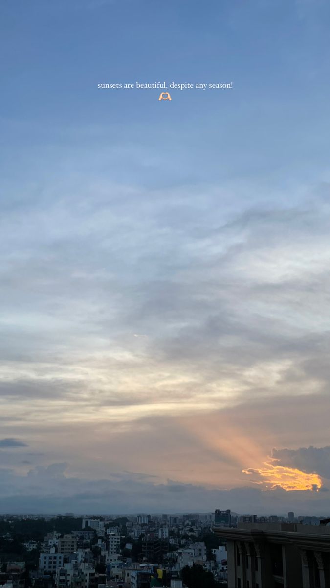 the sun is setting over a city with buildings in the foreground and clouds in the background