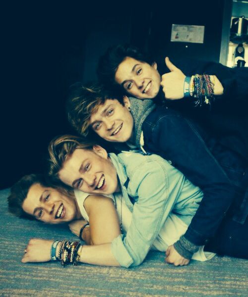 four young people are posing for a photo together on a bed with their arms around each other