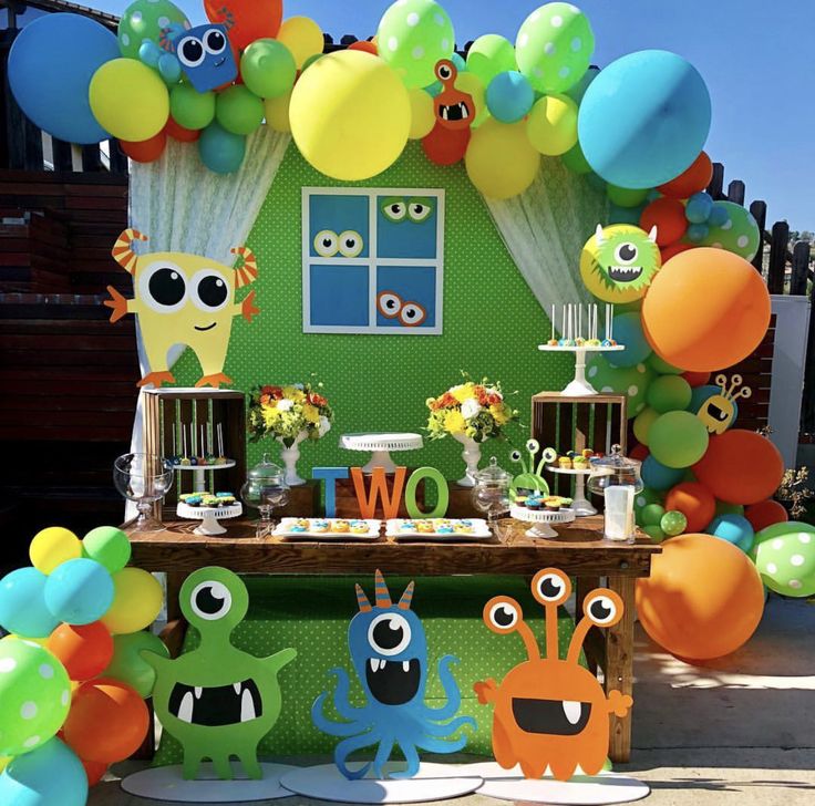 an outdoor birthday party with balloons, paper cutouts and monster decorations on the table