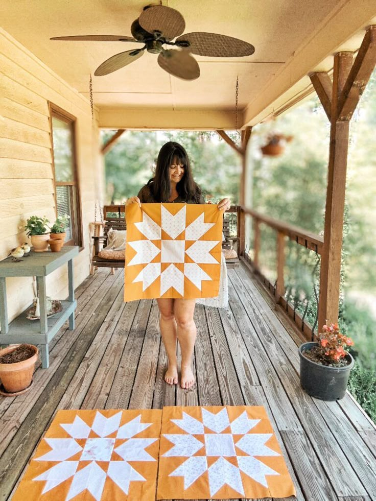 a woman standing on a porch holding an orange and white piece of cloth with stars