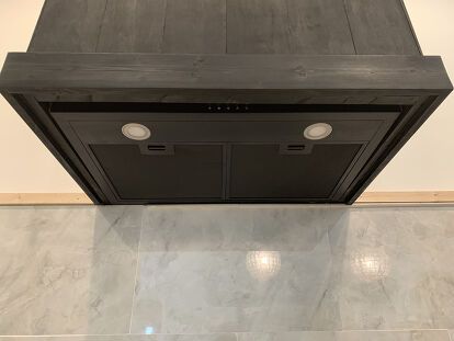 a black stove top oven sitting on top of a white tiled floor next to a wall