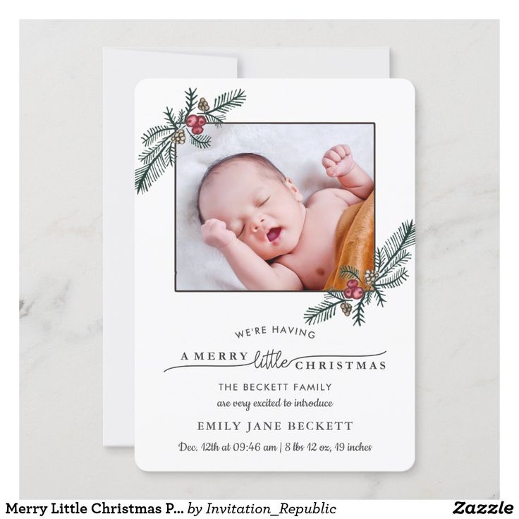 a baby's first christmas card with a photo and evergreen branches on it, in white