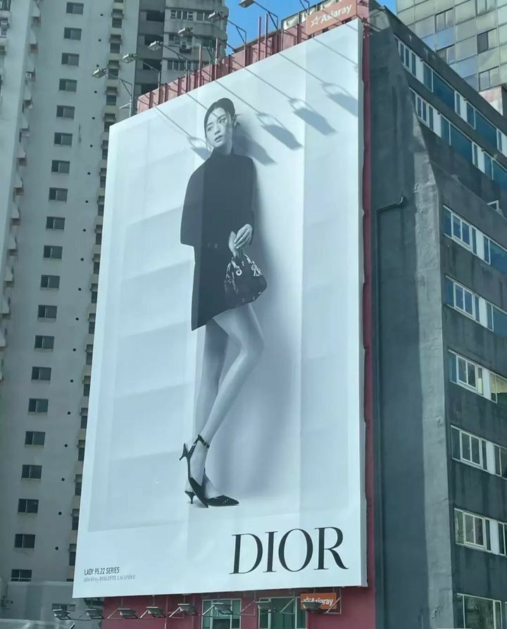 a large advertisement on the side of a building with a woman in black dress and high heels