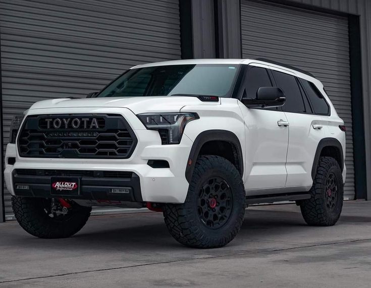 a white toyota truck parked in front of a garage door with the words toyota on it