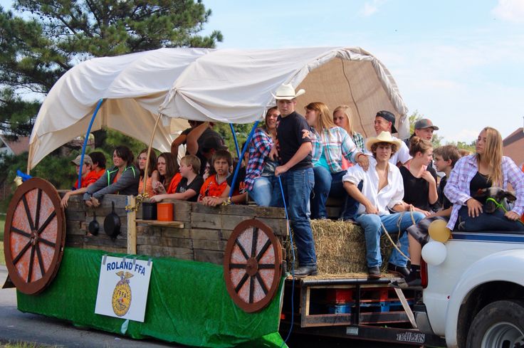 a group of people riding on the back of a truck with hay in the bed