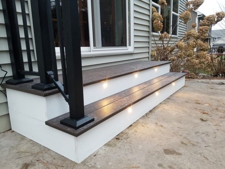 some lights are lit up on the side of a house's front porch steps