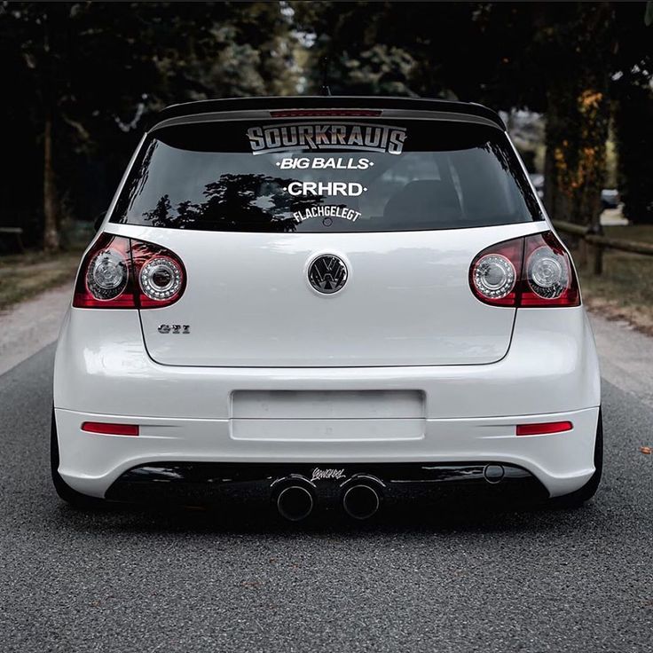 the back end of a white car with stickers on it's bumpers