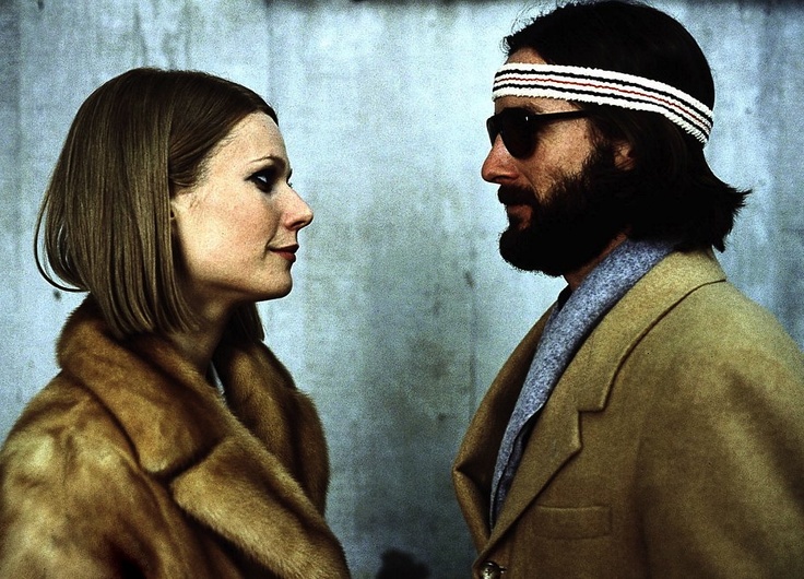 a man and woman standing next to each other in front of a blue wall wearing headbands