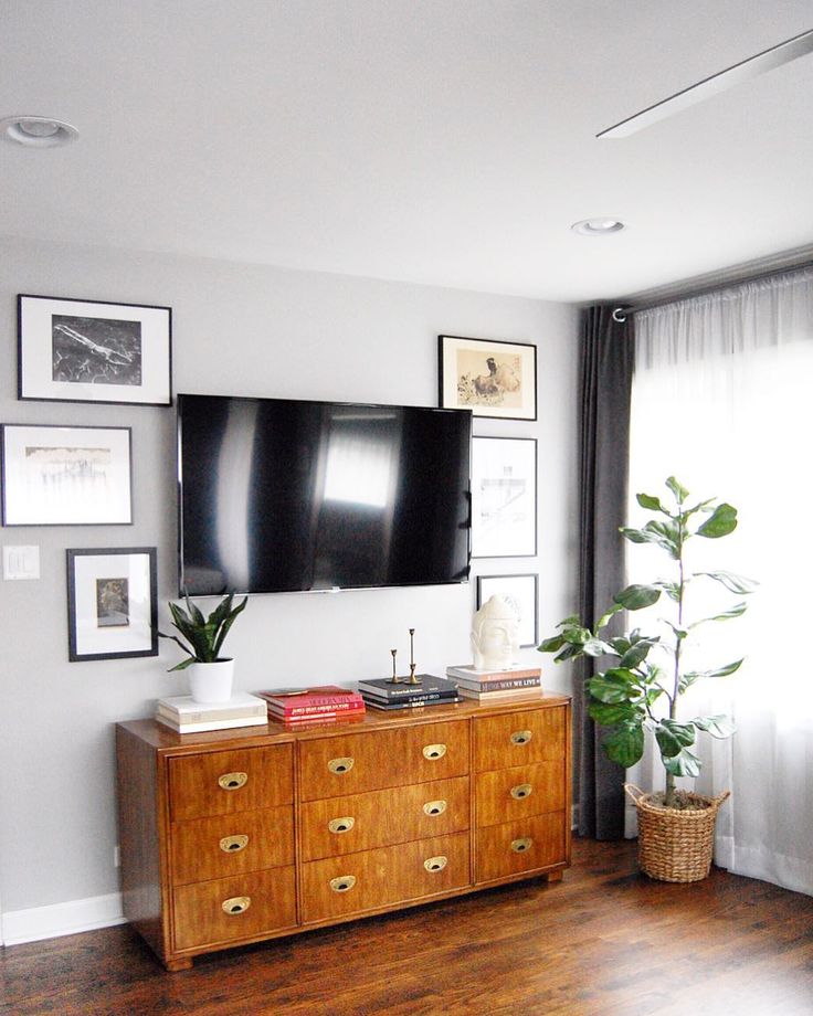 a flat screen tv mounted to the side of a wooden dresser in a living room