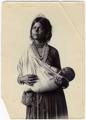 an old black and white photo of a woman holding a baby in her arms,