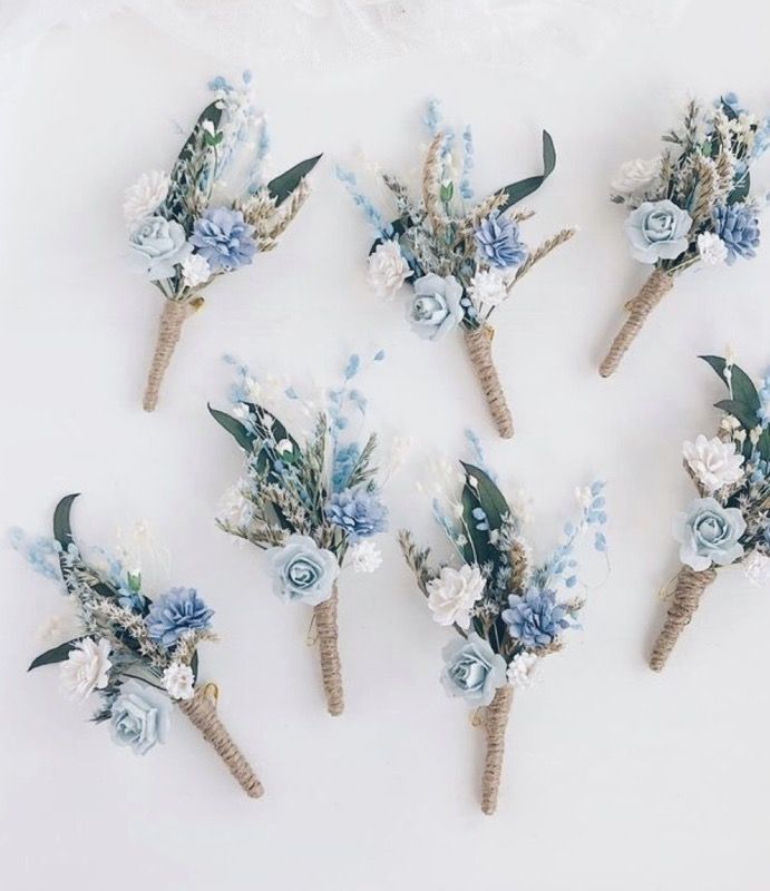 six blue and white boutions are arranged on a white surface with sheer fabric in the background