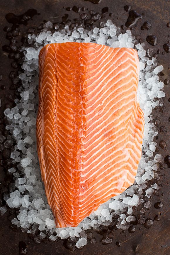 a piece of salmon sitting on top of sea salt