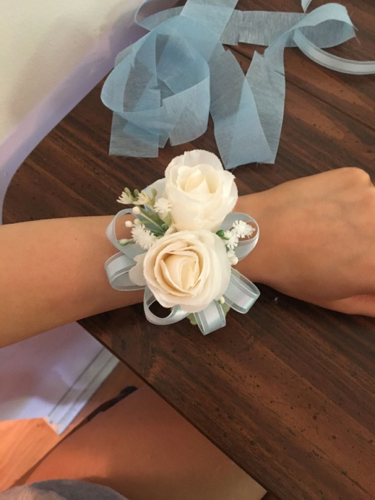 a woman's hand with a wrist corsage on it