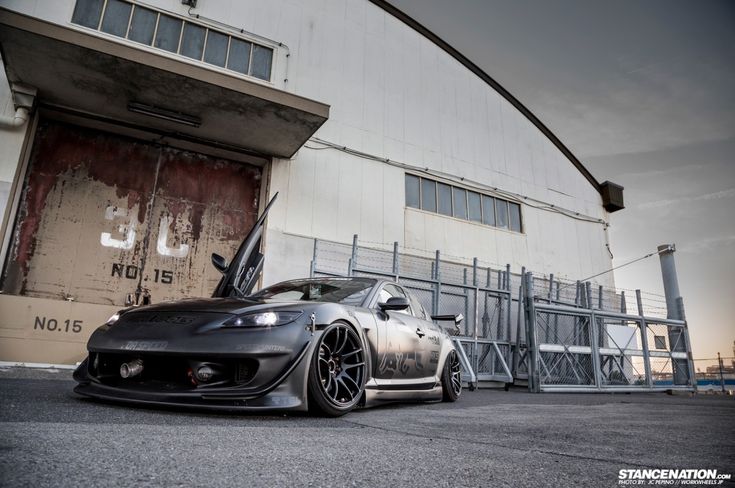 a grey sports car parked in front of a building