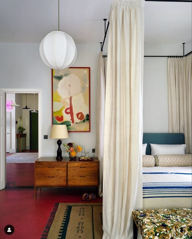 a bedroom with a canopy bed and colorful rugs on the floor in front of it