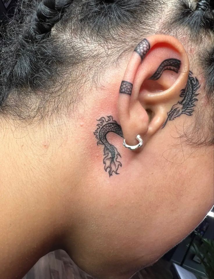 a woman with tattoos on her ear and behind the ear is a small dragon tattoo