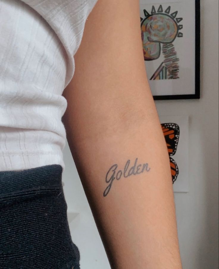 a woman with a tattoo on her arm that says golden in cursive writing