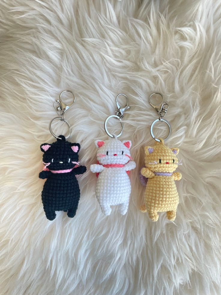 three crocheted keychains with cats on them sitting on a furry surface