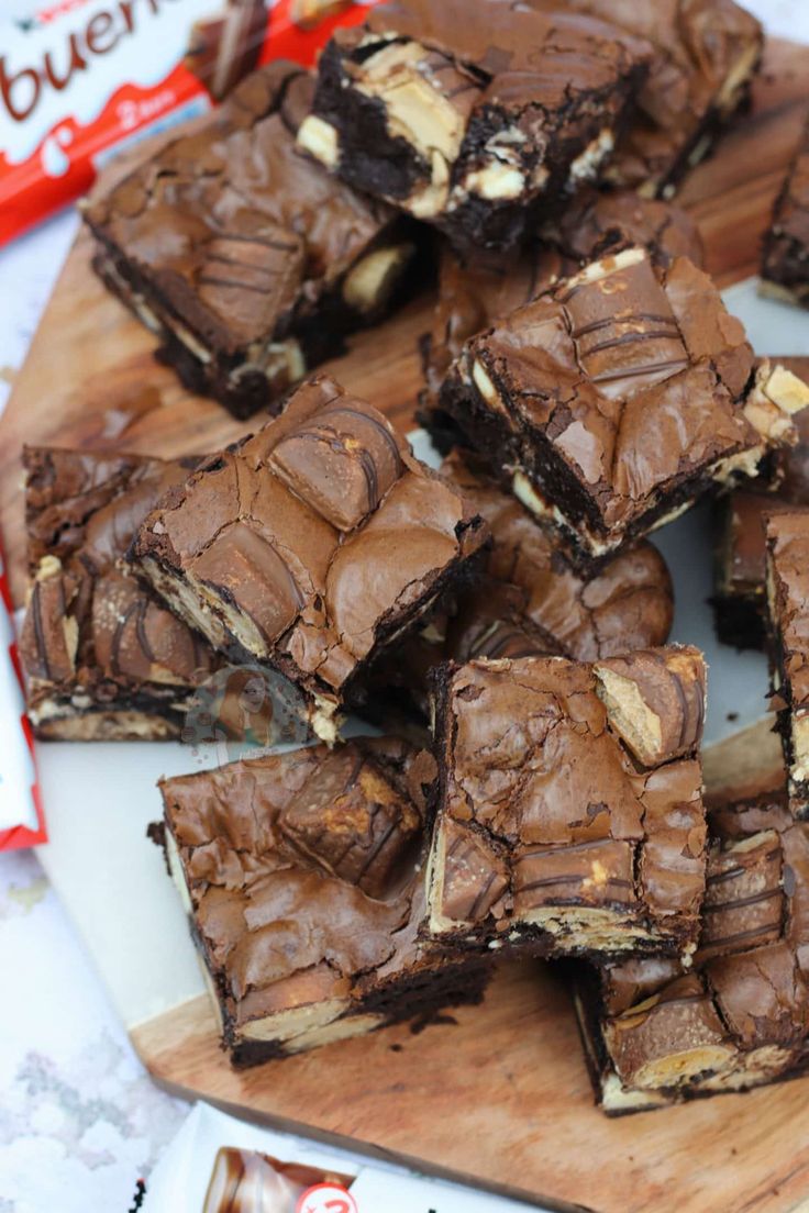 chocolate brownies cut into squares on a cutting board next to a bag of candy