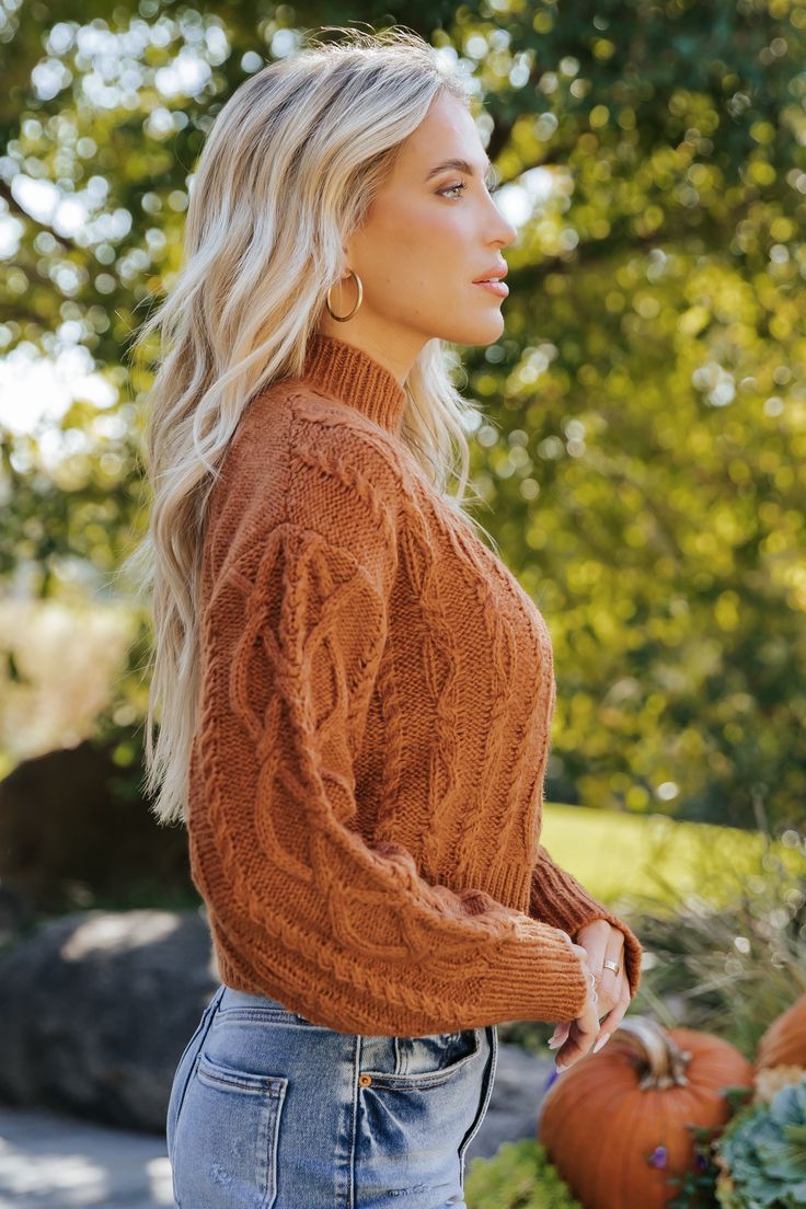 This Burnt Orange Cable Knit Sweater is a cozy and stylish essential for cooler days! This sweater features long sleeves with ribbed cuffs, drop shoulders for a relaxed fit, and a classic mock neckline. The intricate cable knit design adds texture and warmth, complemented by ribbed detailing at the neckline and hem. It's a perfect addition to your fall and winter wardrobe! Style with jeans, ankle booties, and a cute little crossbody bag to complete the look. Trendy Fall Chunky Knit Turtleneck, Trendy Chunky Knit Turtleneck For Fall, Fall Cable Knit Turtleneck, Trendy Cable Knit Turtleneck For Winter, Cable Knit Long Sleeve Turtleneck For Layering, Long Sleeve Cable Knit Turtleneck For Layering, Trendy High Neck Cable Knit Sweater, Trendy Cable Knit Sweater For Fall, Solid Knit Turtleneck Cropped Sweater