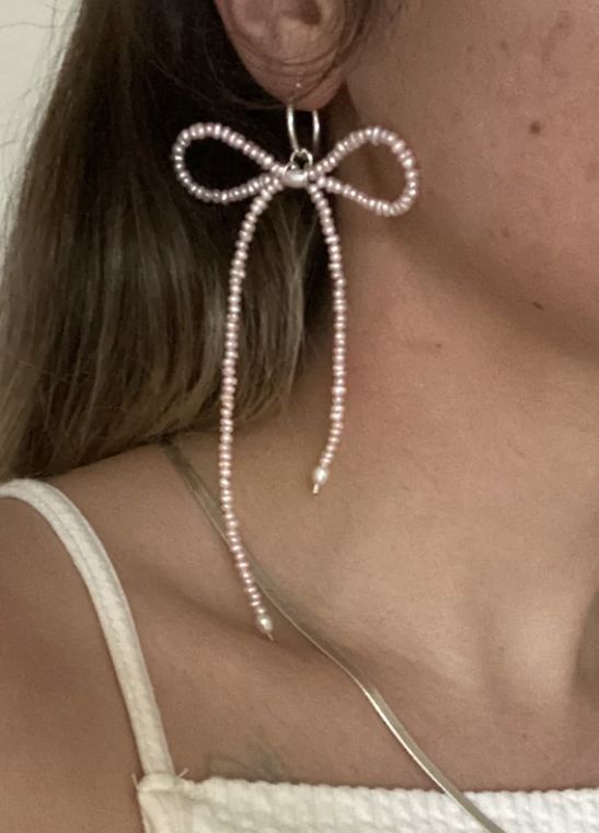 a close up of a person wearing some kind of earring with pearls on it