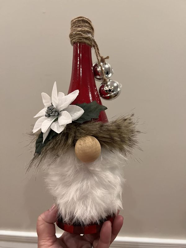 a hand holding a red and white gnome ornament