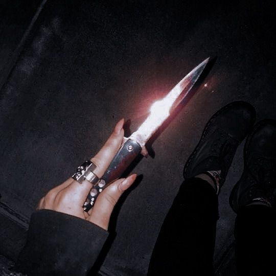 a person holding a knife in their hand with the light shining on it's blade