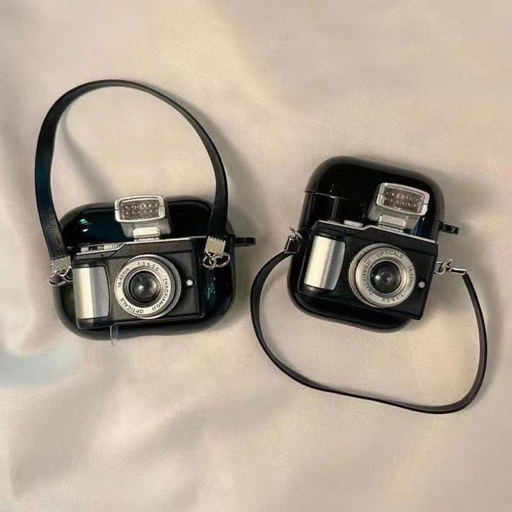 two cameras sitting next to each other on a bed