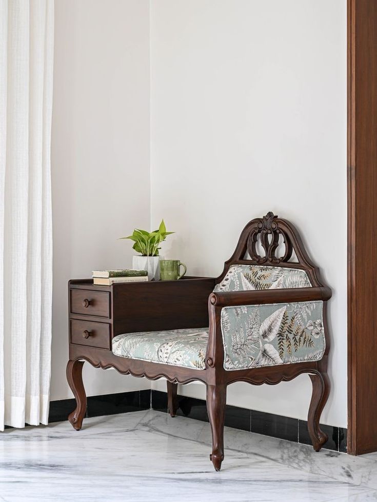 a wooden bench sitting next to a white wall with a potted plant on top of it