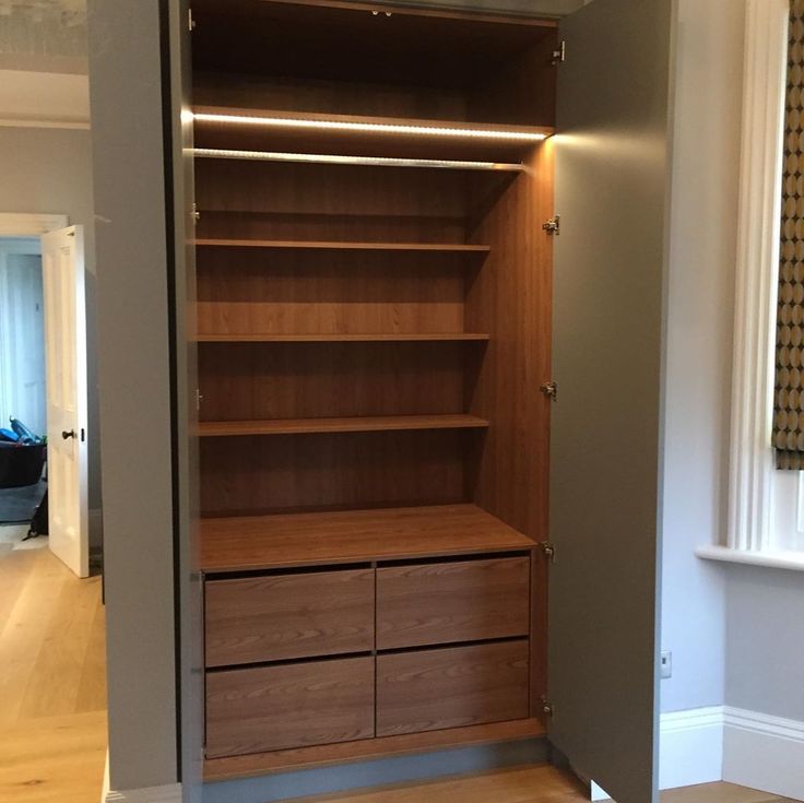 an empty closet with wooden shelves and drawers