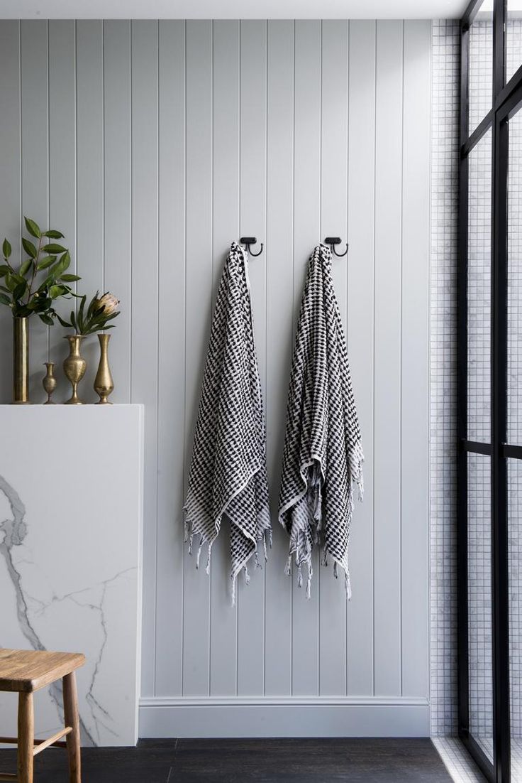 two black and white towels hanging on the wall next to a wooden bench in a bathroom