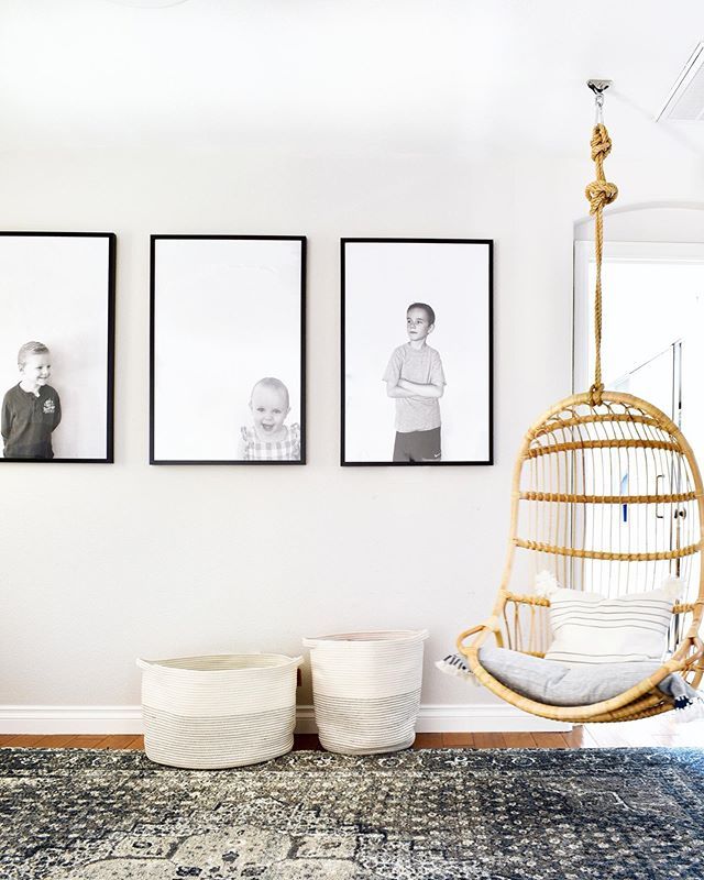 three black and white photos hang on the wall above a swing chair in a living room