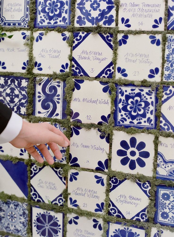 a person is placing blue and white tiles on the wall to display their wedding date