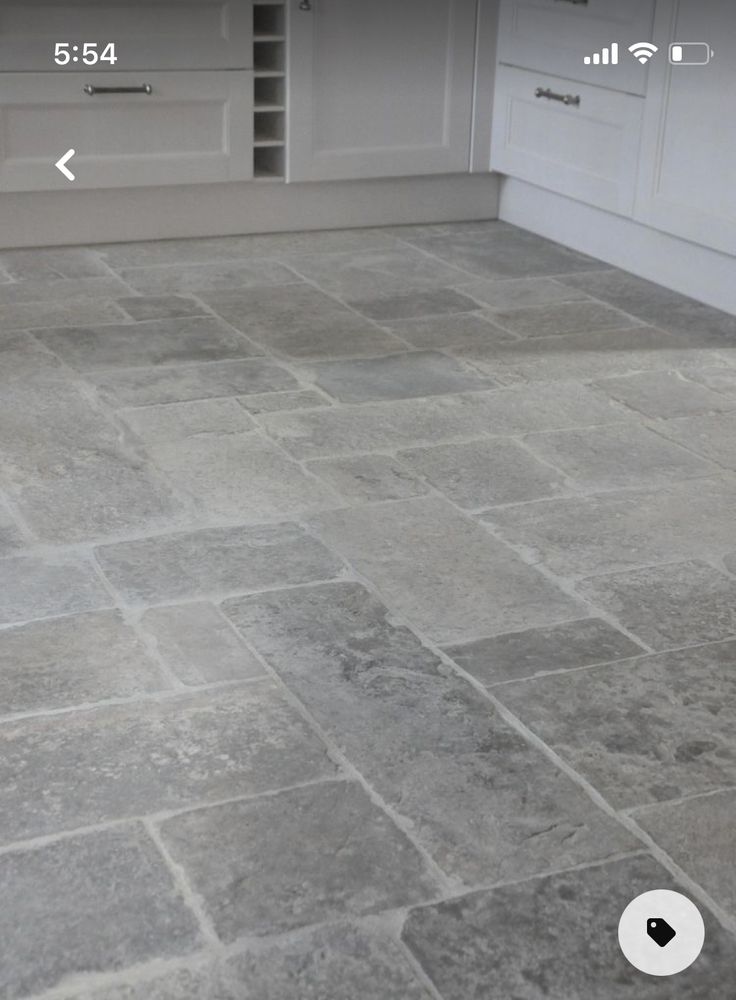 a kitchen with white cabinets and gray tile flooring