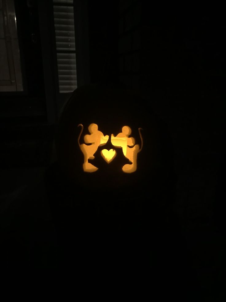 a pumpkin carved to look like mickey and minnie mouses face in the dark with their faces lit up