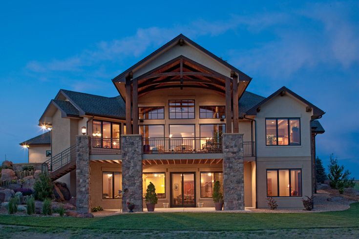 a large house with lots of windows and stone pillars on the front of it at night