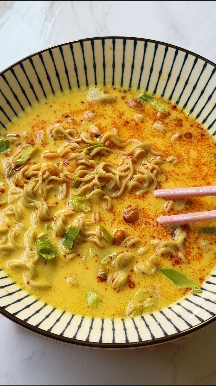 a bowl filled with noodles and vegetables next to chopsticks