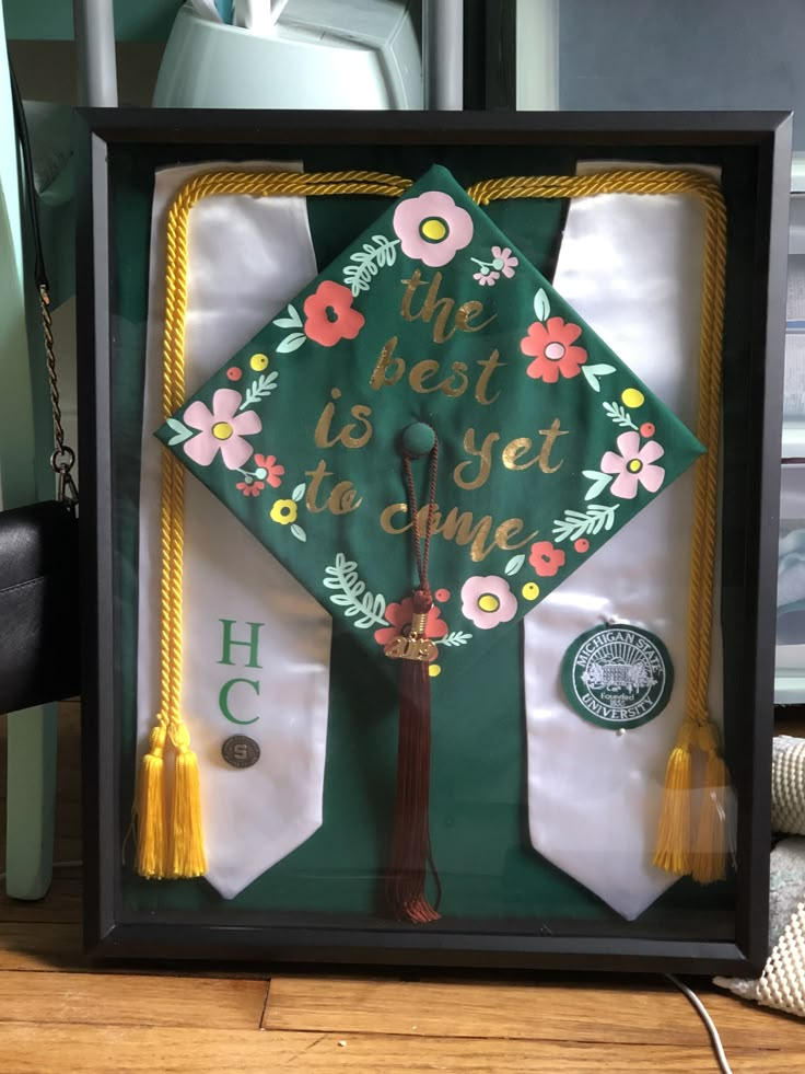 a green graduation cap with flowers and the words, the best is yet to one