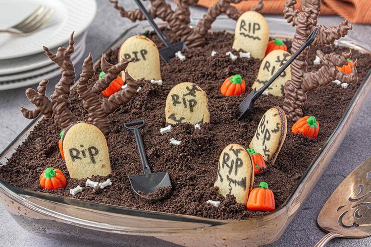 a cake decorated to look like graveyard with tombstones and pumpkins in the dirt