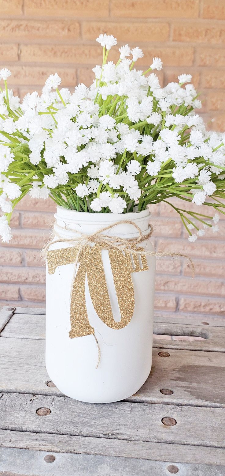 a mason jar filled with white flowers on top of a wooden table