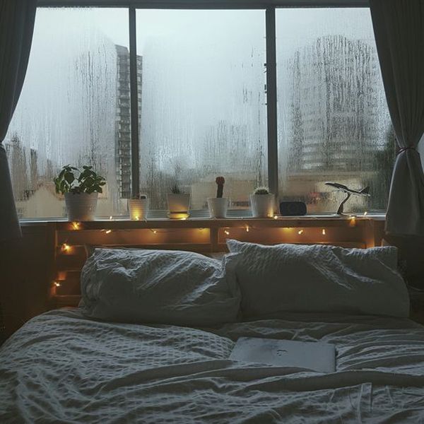 a bed sitting in front of a window covered in rain