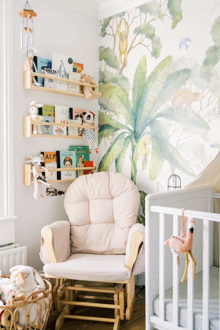 a baby's room with a chair, crib and wall mural