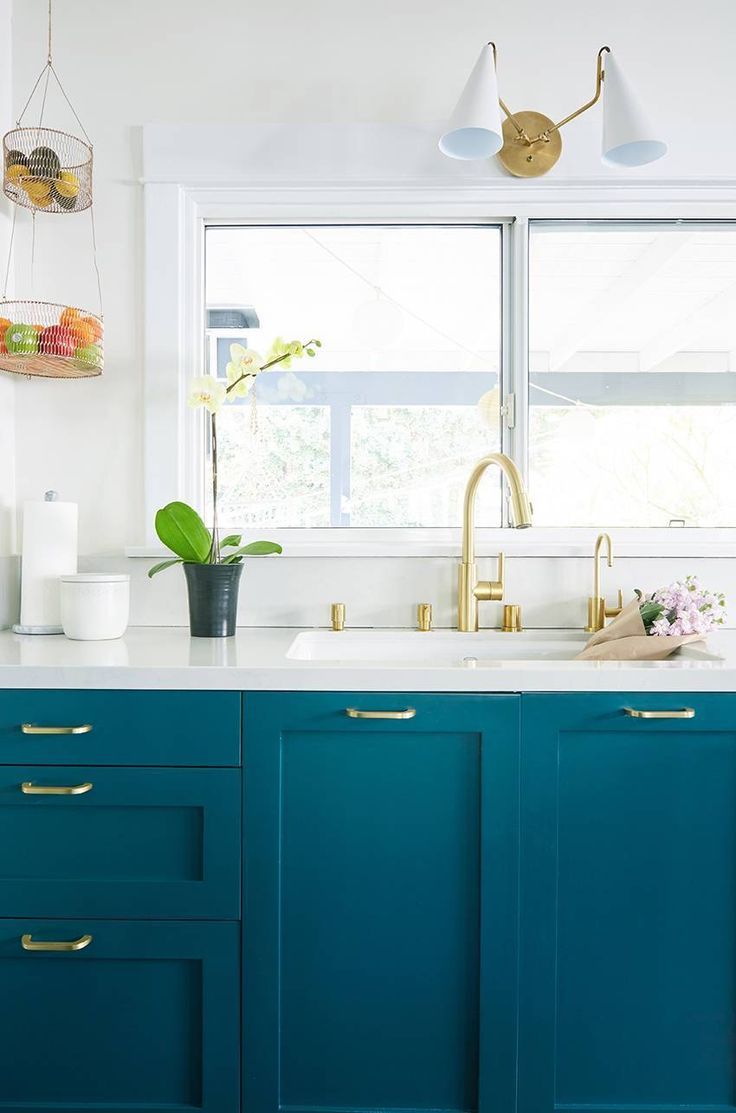 a kitchen with blue cabinets and gold pulls on the handles, along with white counter tops