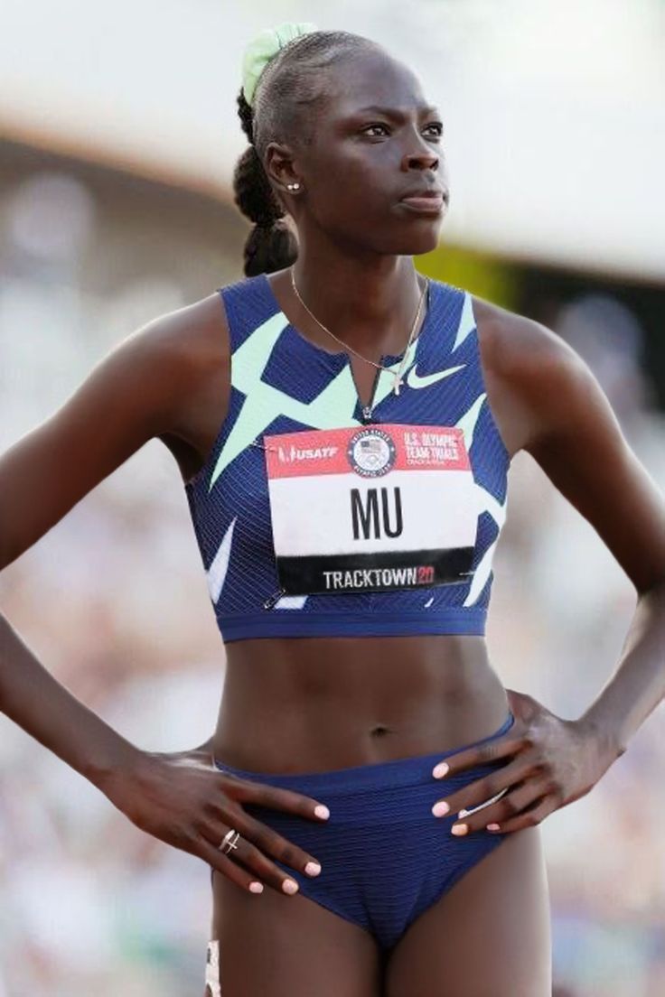 a woman standing on top of a track wearing a blue and white suit with her hands on her hips